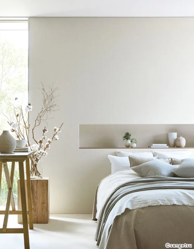 Tường dán giấy vân dệt màu be phía sau đầu giường, bàn gỗ nhỏ và cành bông khô, mã SGM1282